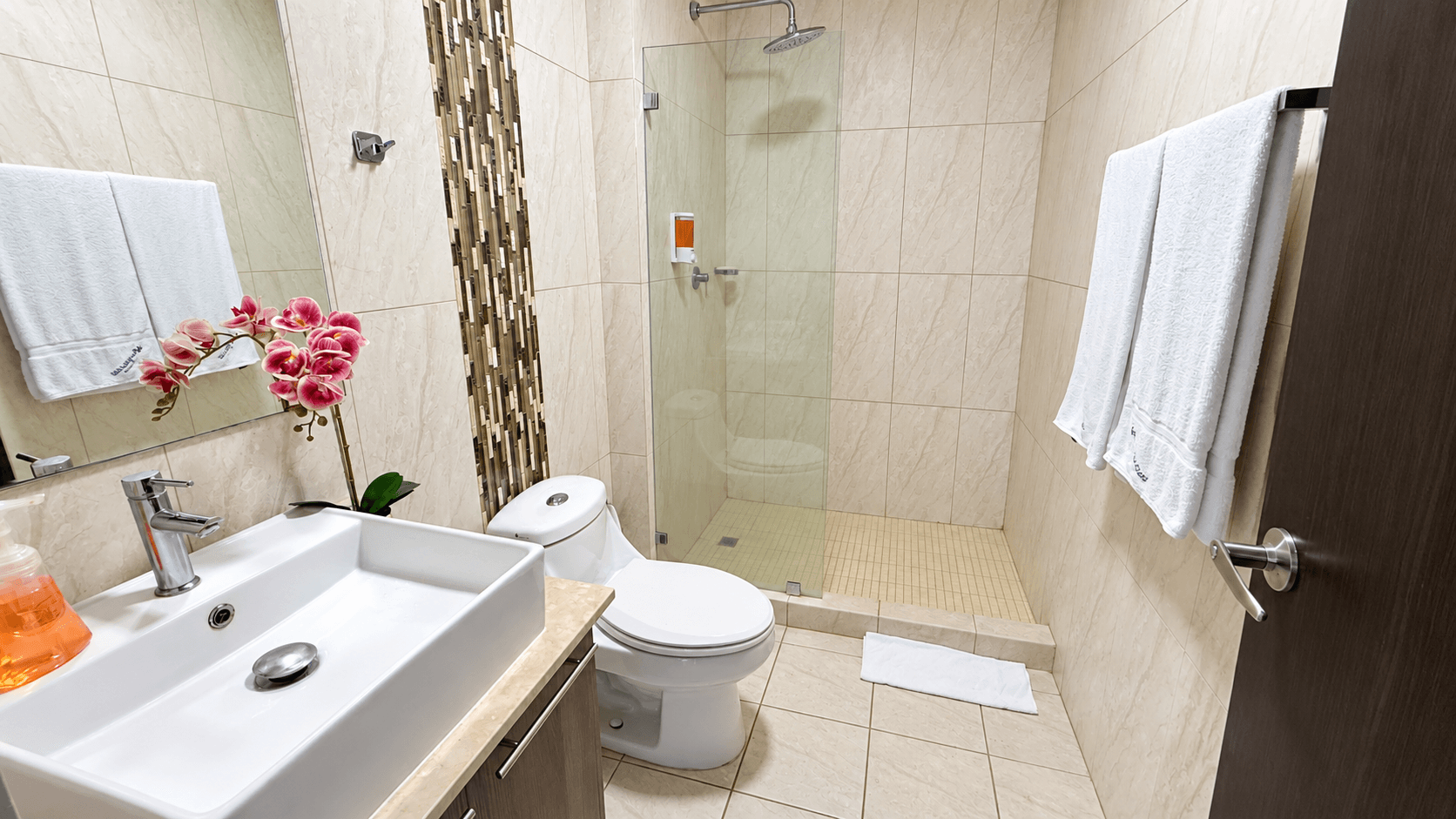 Segundo baño completo con azulejos beige y ducha de vidrio
